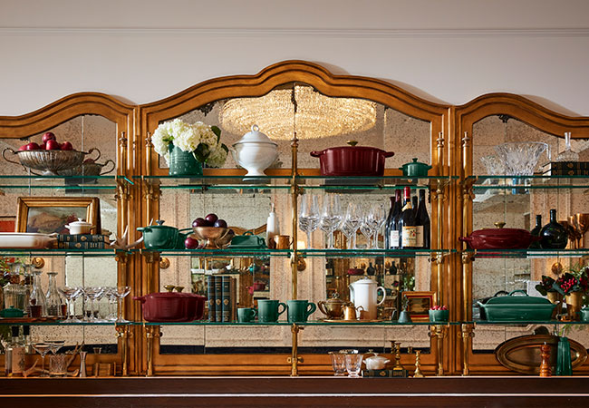 elegant shelves filled with decor and cookware in wine red and verdant green
